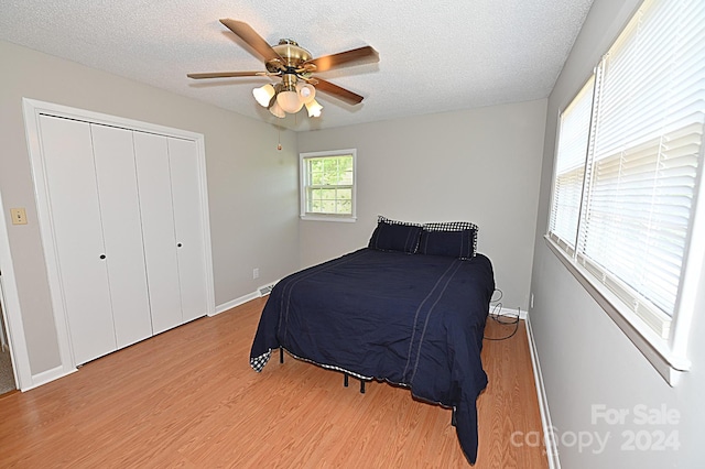 bedroom with light wood-type flooring, a ceiling fan, and a textured ceiling