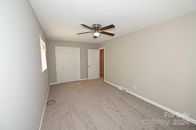 unfurnished bedroom with a ceiling fan, carpet, a textured ceiling, and baseboards