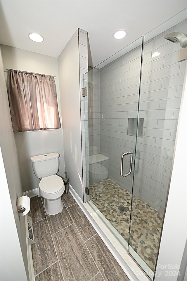 bathroom featuring toilet, a shower stall, baseboards, and recessed lighting