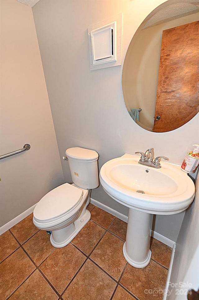 bathroom with toilet, baseboards, and tile patterned floors