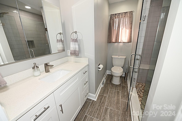 bathroom featuring toilet, wood finish floors, vanity, baseboards, and a shower stall