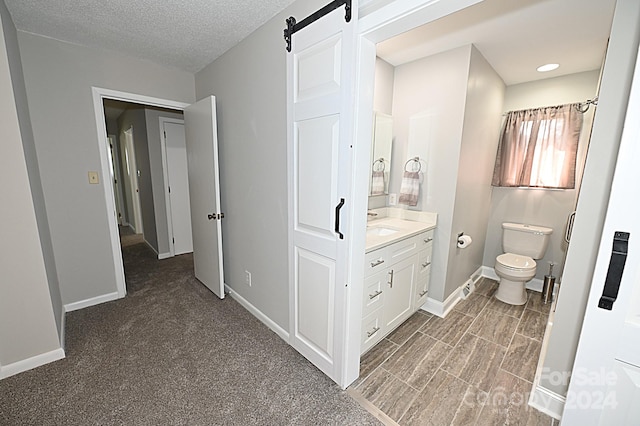 bathroom with toilet, baseboards, a textured ceiling, and vanity