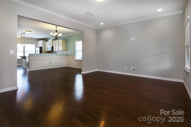 unfurnished living room with ornamental molding, a chandelier, and dark hardwood / wood-style flooring