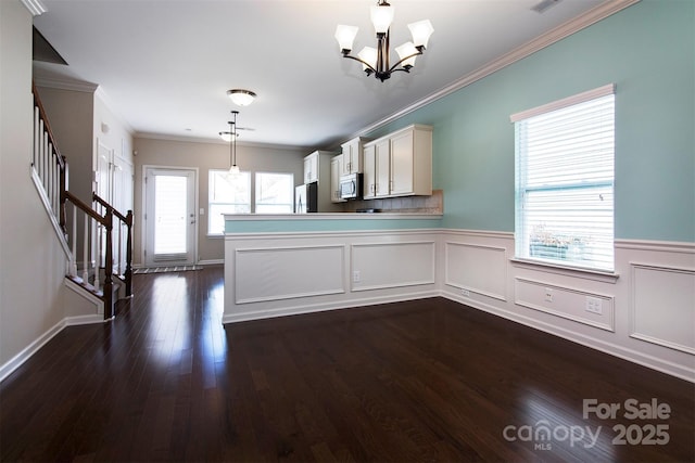 kitchen featuring dark wood-type flooring, hanging light fixtures, stainless steel appliances, ornamental molding, and kitchen peninsula