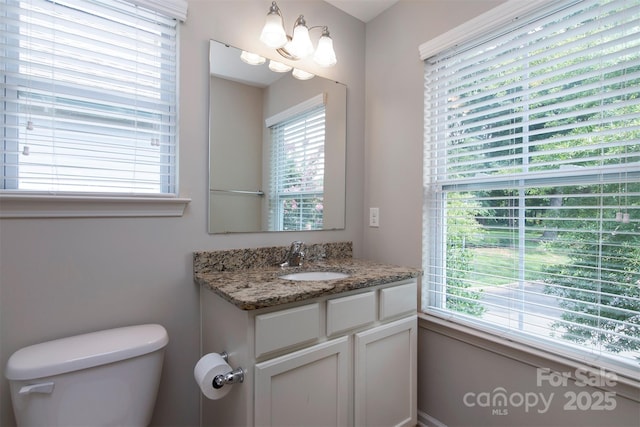 bathroom featuring vanity, a wealth of natural light, a chandelier, and toilet