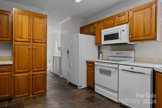 kitchen featuring dark tile patterned flooring, crown molding, washing machine and dryer, and white appliances