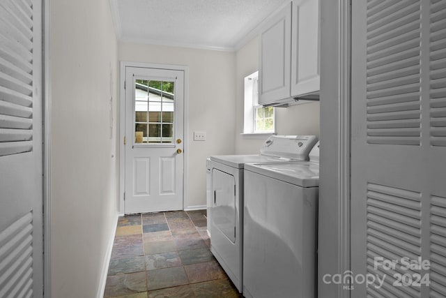 washroom featuring dark tile patterned flooring, plenty of natural light, washer and clothes dryer, and cabinets