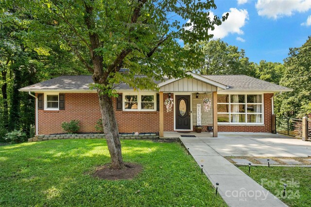 ranch-style house with a shingled roof, a front lawn, and brick siding