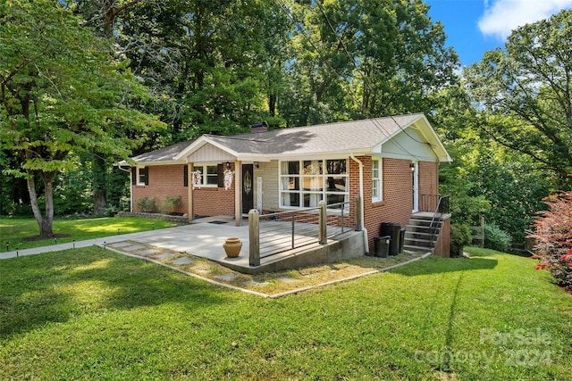 ranch-style house featuring a front yard, a patio area, brick siding, and a chimney