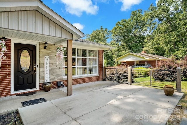 doorway to property featuring brick siding and fence