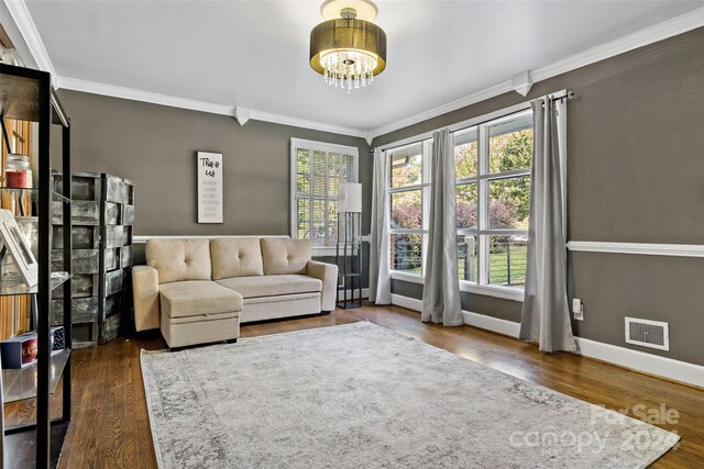 living room with a notable chandelier, ornamental molding, and dark hardwood / wood-style flooring