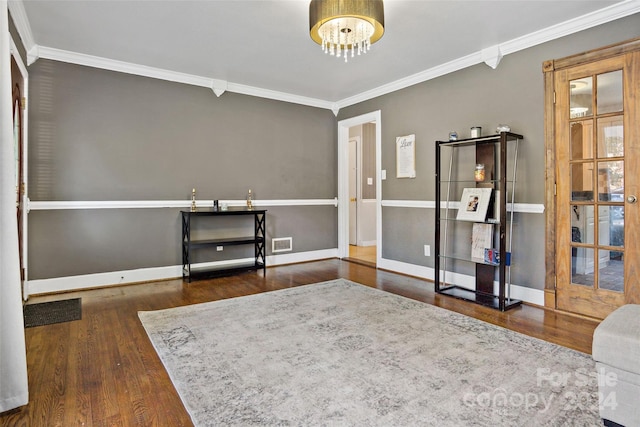 interior space featuring ornamental molding, wood finished floors, visible vents, and baseboards