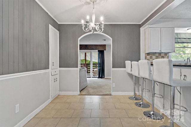 interior space with arched walkways, a notable chandelier, crown molding, and baseboards