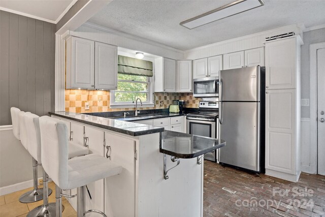 kitchen with a kitchen breakfast bar, sink, tasteful backsplash, stainless steel appliances, and kitchen peninsula