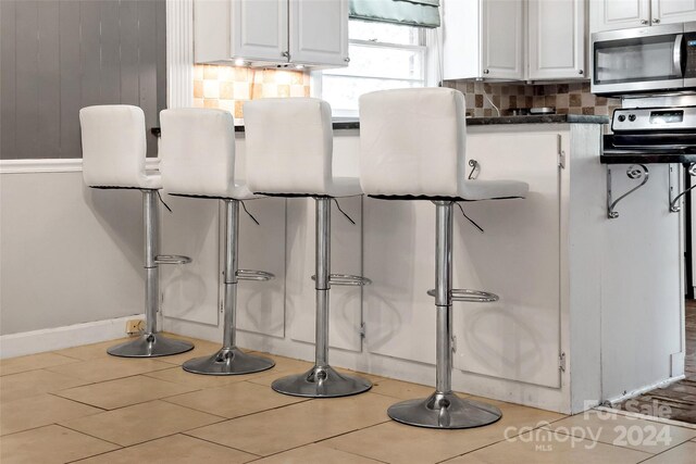 interior space with white cabinets, tile patterned flooring, and tasteful backsplash