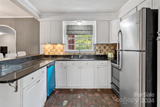 kitchen featuring stainless steel appliances, decorative backsplash, ornamental molding, white cabinetry, and sink