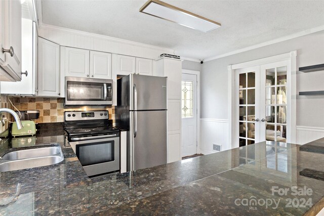 kitchen featuring stainless steel appliances, ornamental molding, french doors, sink, and white cabinets