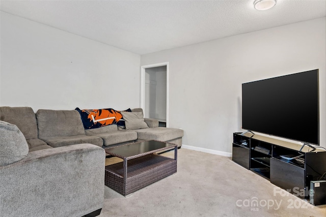 carpeted living room featuring baseboards and a textured ceiling