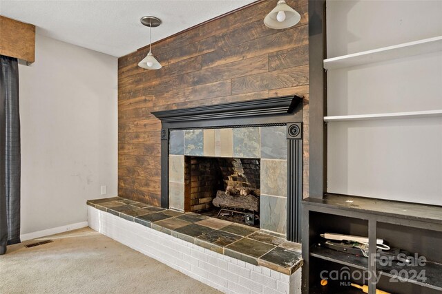 interior details with wood walls, a tile fireplace, and carpet flooring