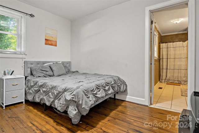 bedroom featuring ensuite bathroom and dark hardwood / wood-style floors