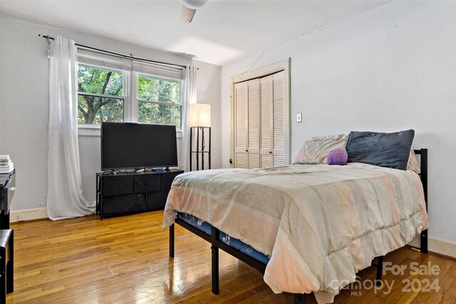 bedroom with light wood-type flooring, ceiling fan, and a closet