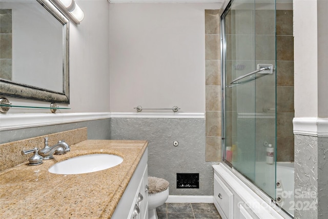 bathroom featuring tile patterned floors, a shower with door, vanity, and toilet