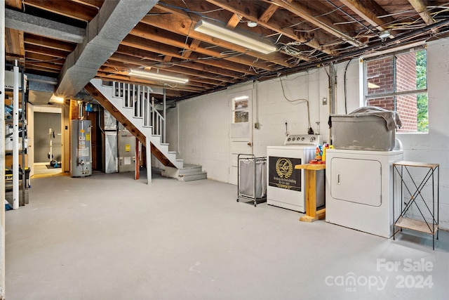 below grade area featuring gas water heater, stairway, and separate washer and dryer