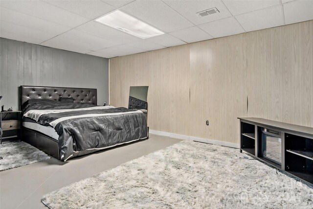 bedroom with a drop ceiling and wooden walls