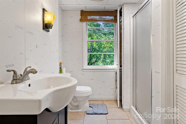 bathroom featuring a drop ceiling, toilet, vanity, tile patterned floors, and a shower with shower door