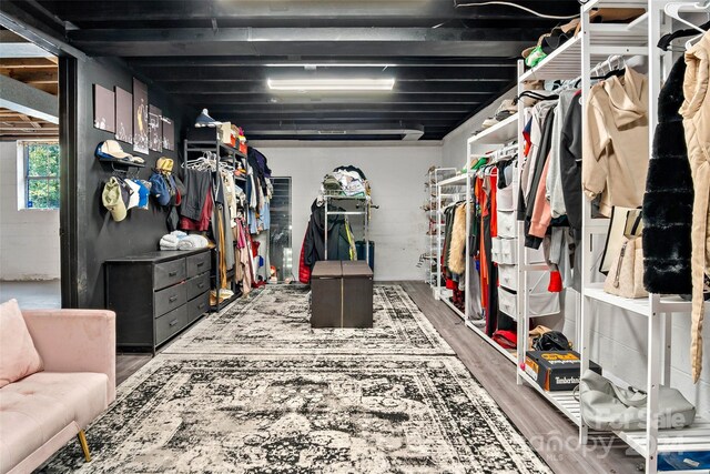 walk in closet with beam ceiling and hardwood / wood-style flooring