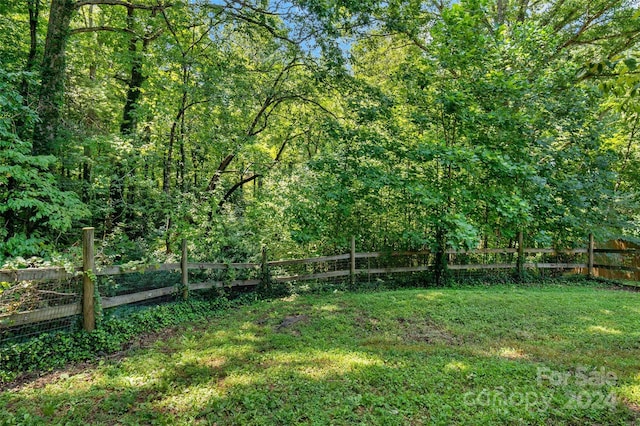 view of yard featuring a wooded view and fence