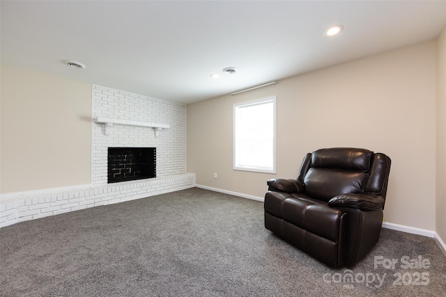 living area featuring dark colored carpet and a brick fireplace