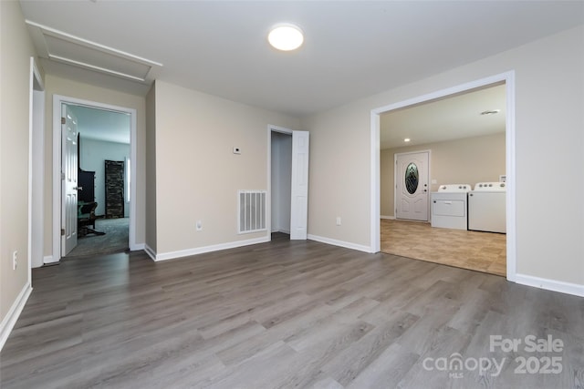 empty room with washing machine and clothes dryer and hardwood / wood-style flooring