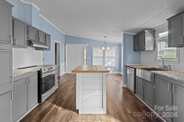 kitchen with vaulted ceiling, dark wood-type flooring, stainless steel appliances, wooden counters, and a textured ceiling