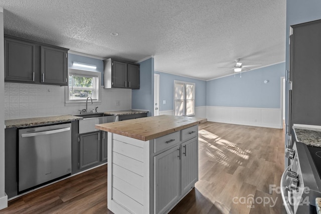 kitchen with dark wood-type flooring, a kitchen island, butcher block counters, gray cabinets, and stainless steel appliances