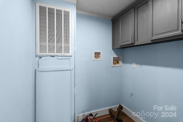 washroom with hookup for a washing machine, a textured ceiling, and cabinets