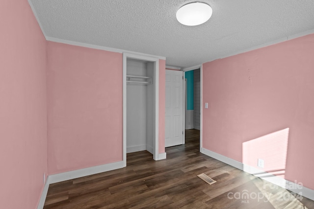 unfurnished bedroom with a closet, a textured ceiling, and dark hardwood / wood-style floors