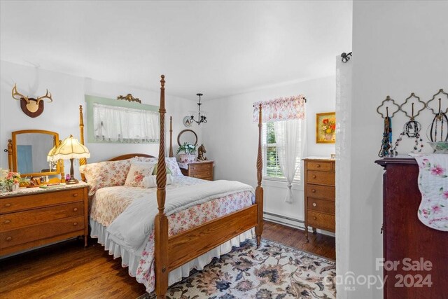 bedroom featuring wood-type flooring and a baseboard heating unit