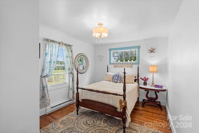 bedroom featuring a baseboard heating unit and hardwood / wood-style floors