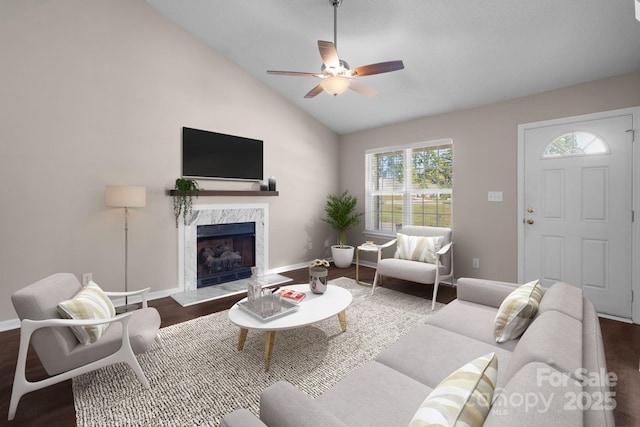 living room featuring a high end fireplace, vaulted ceiling, ceiling fan, and dark wood-type flooring