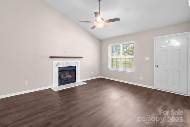 unfurnished living room with dark hardwood / wood-style flooring, a high end fireplace, a healthy amount of sunlight, and vaulted ceiling