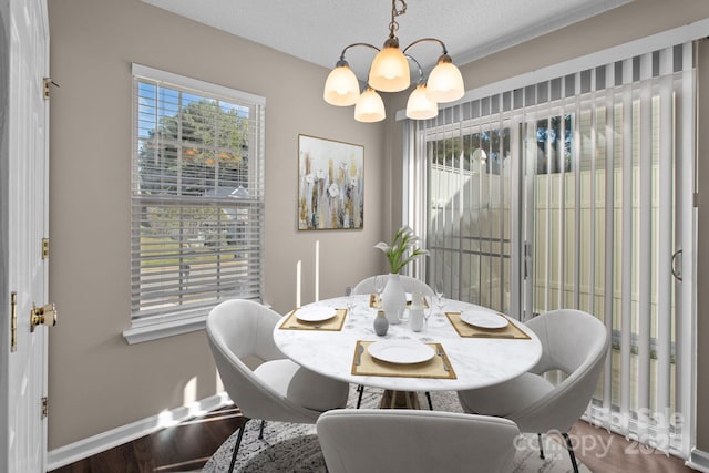 dining area with hardwood / wood-style floors, a textured ceiling, and an inviting chandelier