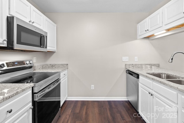 kitchen with white cabinets, light stone counters, sink, and appliances with stainless steel finishes