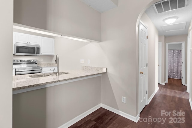 kitchen with dark wood-type flooring, sink, light stone counters, white cabinetry, and stainless steel appliances