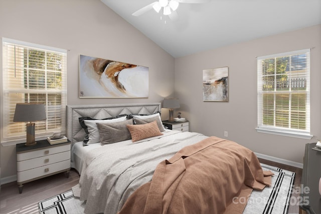 bedroom with multiple windows, ceiling fan, hardwood / wood-style floors, and lofted ceiling