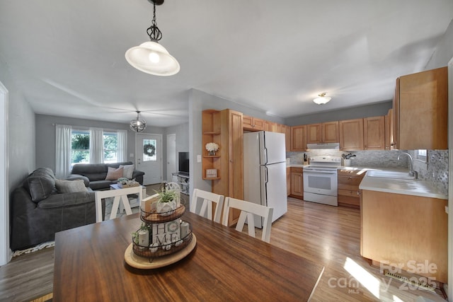 dining space featuring sink, a notable chandelier, and light wood-type flooring