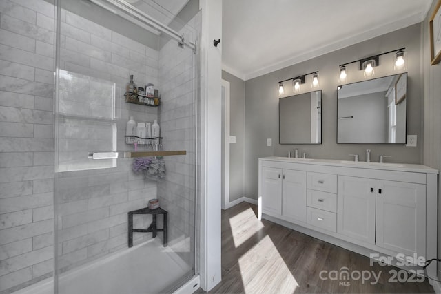 bathroom featuring hardwood / wood-style flooring, vanity, a tile shower, and ornamental molding