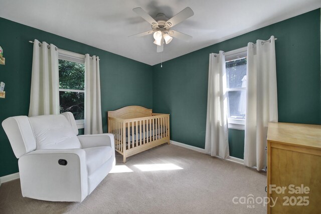 bedroom featuring ceiling fan, carpet, and a crib