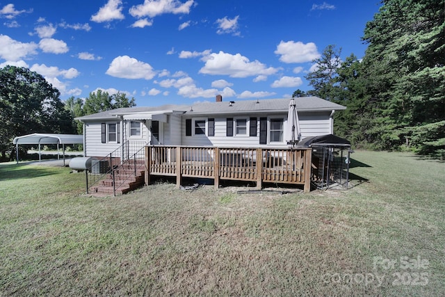 rear view of property featuring a yard, a carport, and a wooden deck