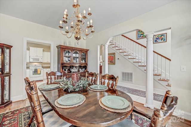 dining space with decorative columns, an inviting chandelier, and light hardwood / wood-style floors